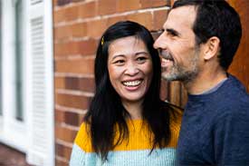 Couple standing in front of brick home smiling
