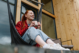 A woman sits in a hammock chair with a mug.