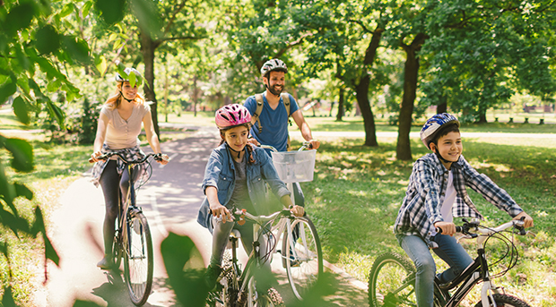 A family rides their bikes through the park.