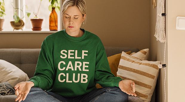 A woman sits on her bed meditating.