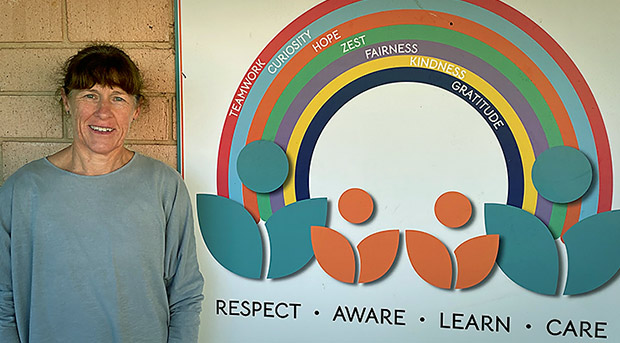 Alison Kerimofski is standing next to a sign with a rainbow hat says "Respect, Aware, Learn, Care"