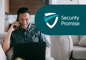 A man sits on a couch, using his laptop and holding a phone to his ear. The Teachers Mutual Bank Security Promise logo is overlaid next to the man.