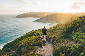 Ethical male hiker walking atop mountain overlooking the ocean