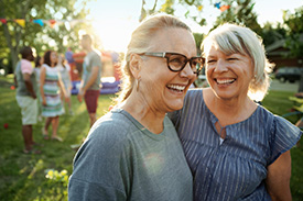 Two women laughing together at outdoor community event