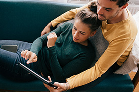 Man and woman sitting on sofa, looking at iPad