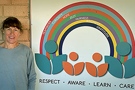 Alison Kerimofski stands in front of a sign with the words 