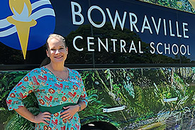 Marcia Bell stands in front of the Bowraville Central School bus. The bus is covered in decals of foliage.