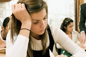 Unhappy girl sitting in class looking at a paper on her desk