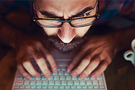 Hacker types with face close to laptop