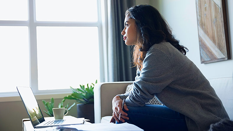 Woman calculating her super on laptop at home. 