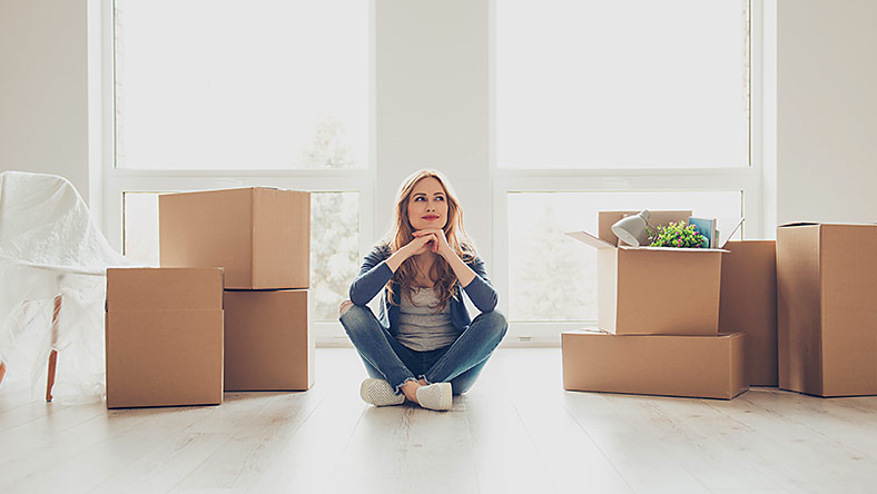Satisfied woman sitting in an empty room with boxes packed 