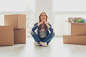 Satisfied woman sitting in an empty room with boxes packed 