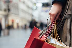 woman on an outside shopping strip holding shopping bags