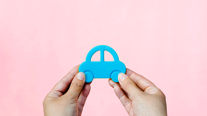 A pair of hands grasp a blue toy car.