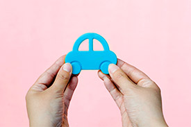 A pair of hands grasp a blue toy car.