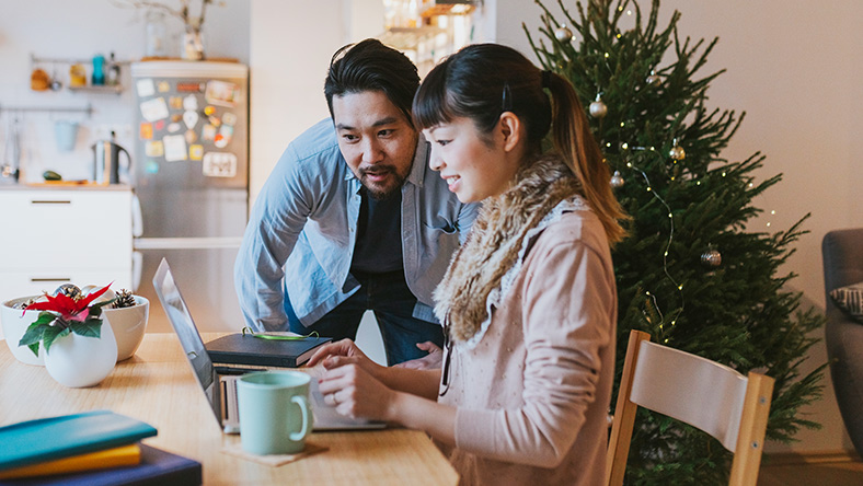 Two people sitting at a table looking at a laptop. 