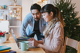 Two people sitting at a table looking at a laptop. 