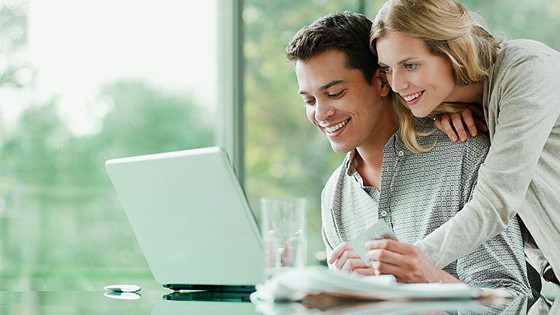 Couple planning solutions to their debt problems using laptop.