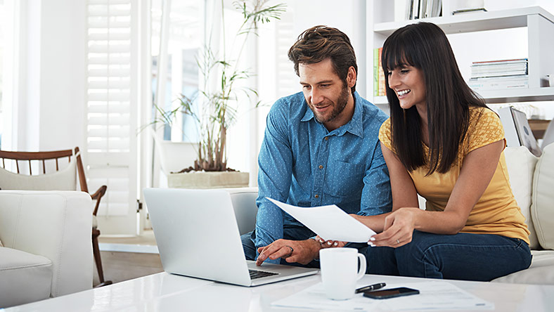 Smiling couple look at laptop