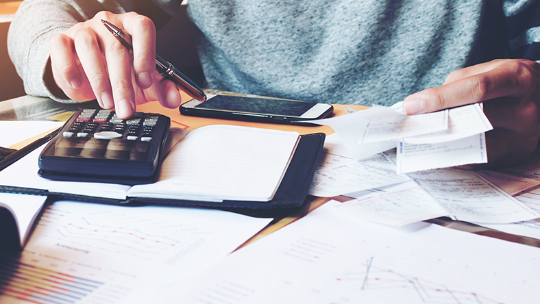 Using a calculator to do taxes, cropped to show just the calculator, hands and torso.