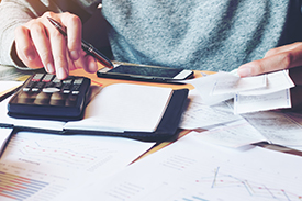 Using a calculator to do taxes, cropped to show just the calculator, hands and torso.