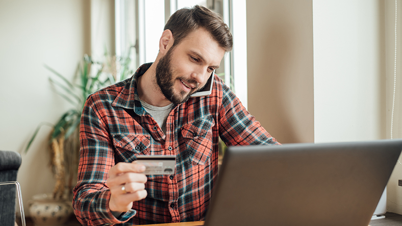 man researching on a laptop while looking at a credit card