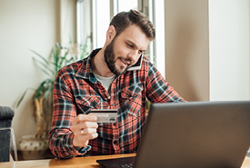 Man researching on a laptop while looking at a credit card. 