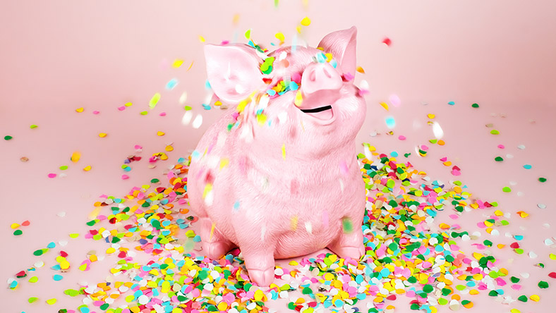 A happy piggy bank is covered in small colourful beads.