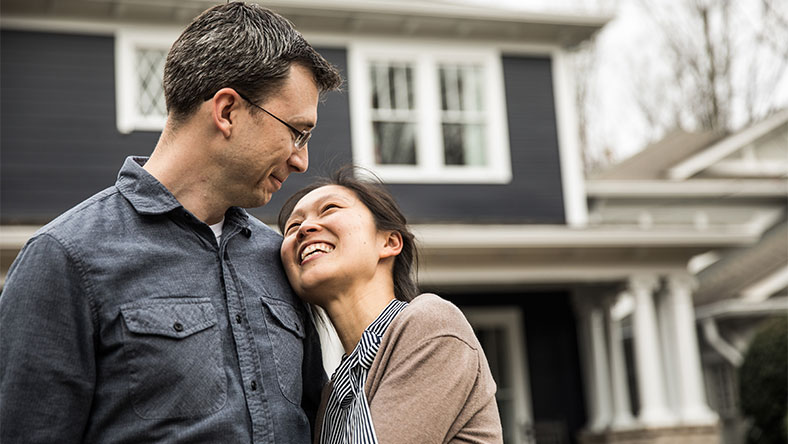 Woman embracing man outside in front of home