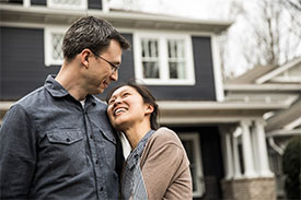 Woman embracing man outside in front of home