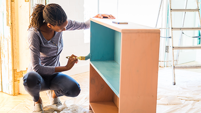 Woman painting bookcase while renovating home