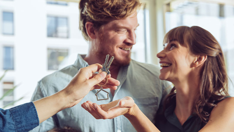 Man and woman looking at each other while being handed keys to new home