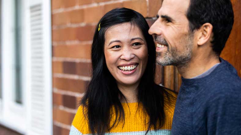 Couple standing in front of brick home smiling