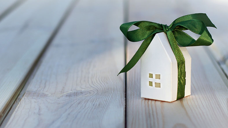 A small toy house wrapped up in a ribbon.