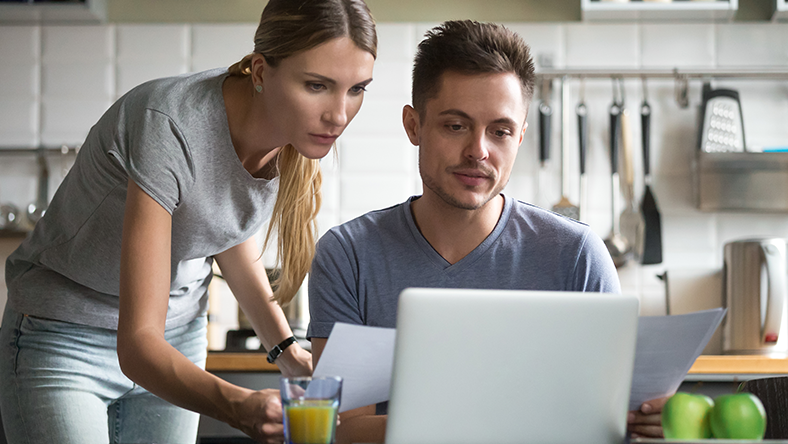 Couple looking at laptop comparing whether to buy or rent home