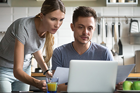 Couple looking at laptop comparing whether to buy or rent home