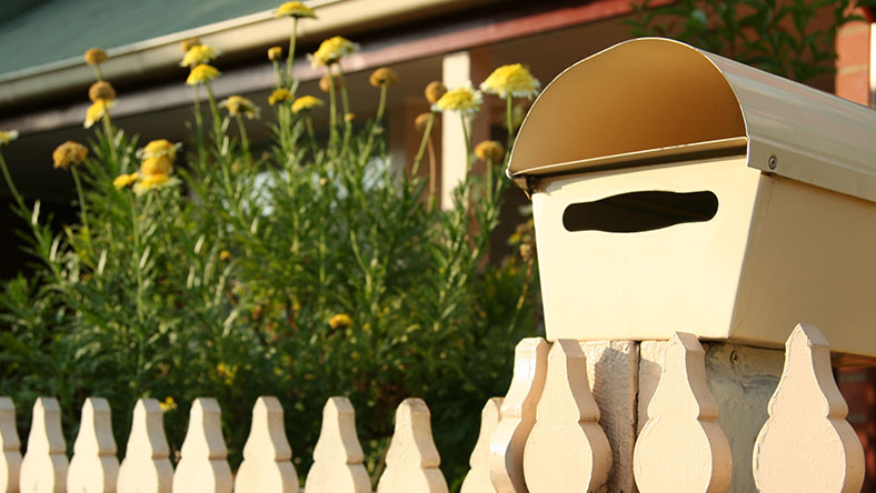 An outside view of a white picket fence and a letterbox of a new home.