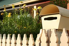 An outside view of a white picket fence and a letterbox of a new home.