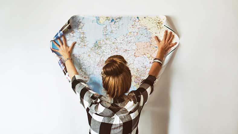 Young women spreading out a global printed map on the wall