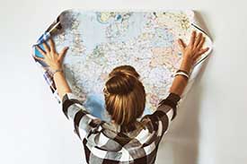 Young women spreading out a global printed map on the wall