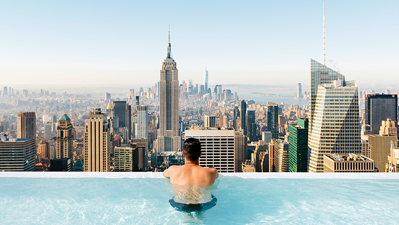 Man in pool, looking out at city view